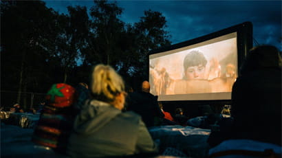 People watching an outdoor cinema screen.