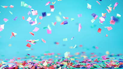 Metallic confetti falling onto table with a bright turquoise blue background.