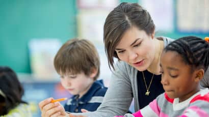 A primary school teacher helping a young child with their work.
