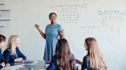 A secondary school teacher standing at the front of the class teaching maths.