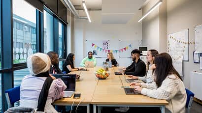 A group of people sitting at a table having a project meeting.