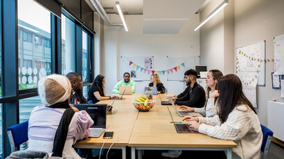 A group of people sitting at a table having a project meeting.
