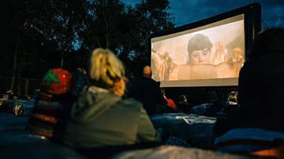 Audience watching an outdoor cinema screening at night.