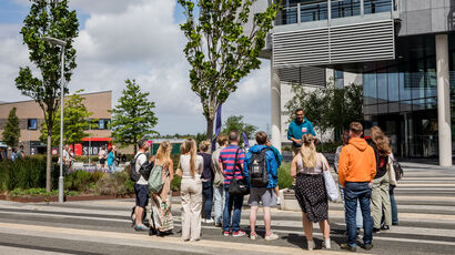 UWE Bristol tour guide speaking to group of prospective students and parents in the plaza on Frenchay Campus.