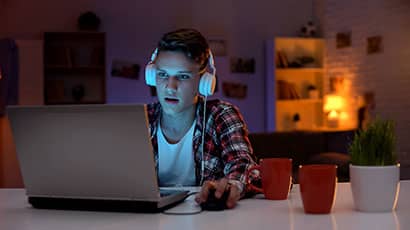 Student with headphones at a laptop