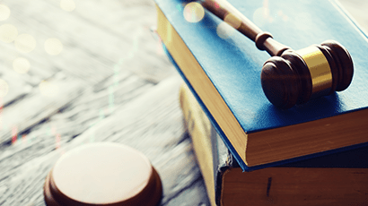 Law gavel lying on a stack of leather bound legal books.