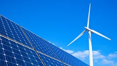 Photograph of renewable energy sources, solar panels and wind turbines.