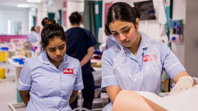 Two student nurses taking part in a patient scenario in the university's replica ward.