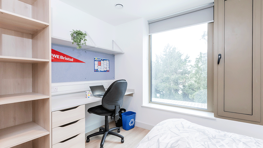 A bedroom desk space with chair and high shelf.