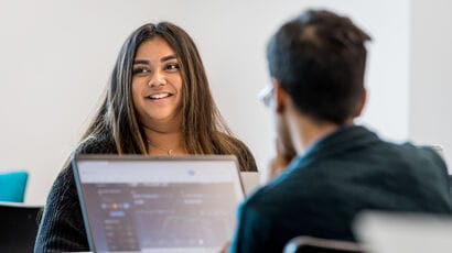 Students analysing data on business performance around a laptop.