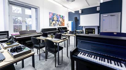 Teaching space in Centre for Music with keyboards and laptops and headphones out on desks.