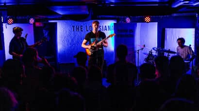 A band performing with blue lighting up the stage.