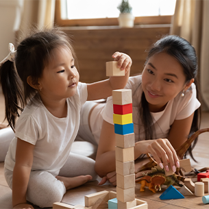Student teacher building a tower of blocks with a child.