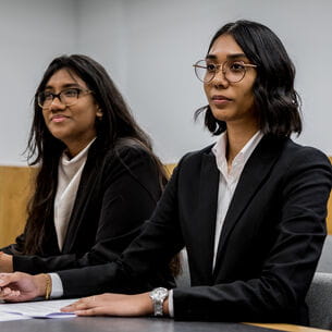 Two law students taking part in a trial a mock courtroom.