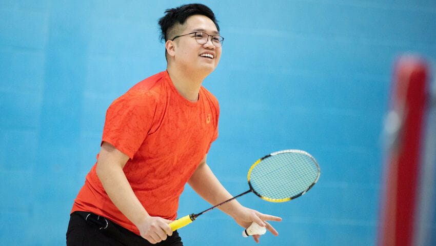 Male student prepares to serve during a badminton match.