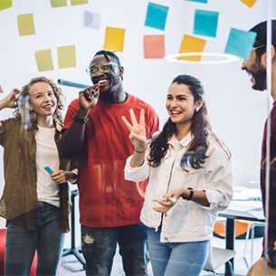 A group of students brainstorming ideas together in front of a glass wall full of sticky notes.