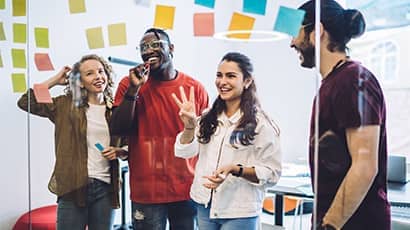 A group of students brainstorming ideas together in front of a glass wall full of sticky notes.