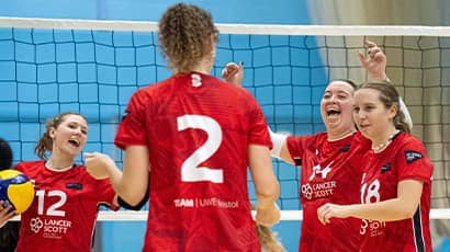 UWE's womens volleyball team celebrating on the court.