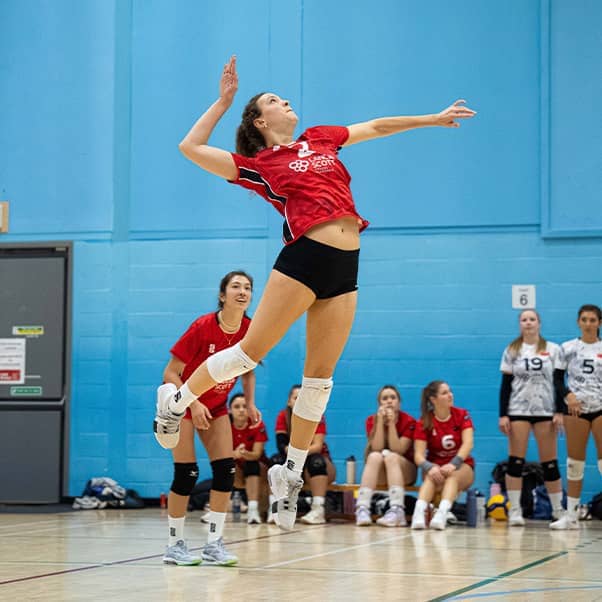 Women's Volleyball student-athlete leaping into the air to return the volleyball.