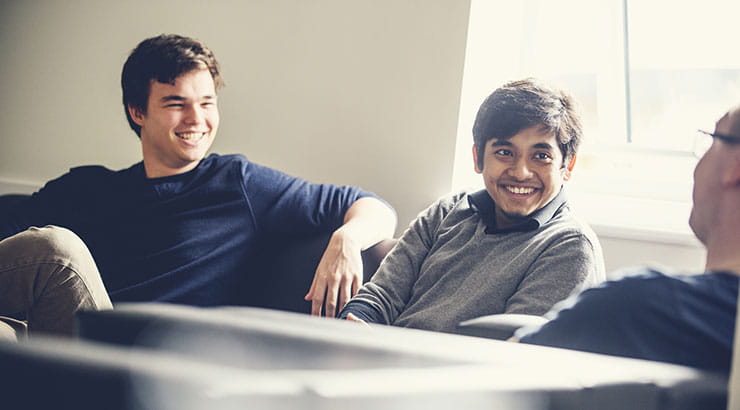 Three students chatting in shared living room in student accommodation