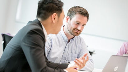 Two people having a discussion in front of a laptop