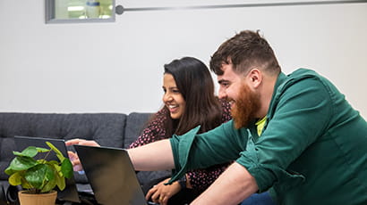 A male and female graduate sitting in front of the laptops in Launch Space.