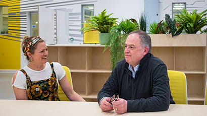 A female and male member of staff sitting at a table in Launch Space.