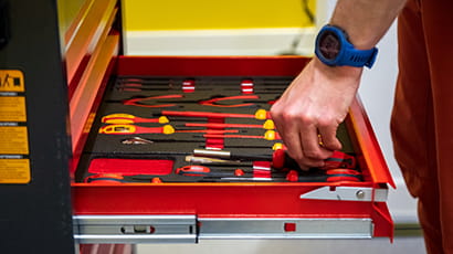 Left hand of a white male with a blue watch reaching into a tool drawer.