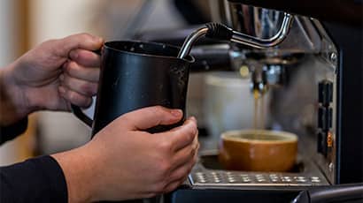 Close up of someone steaming milk with a coffee machine.
