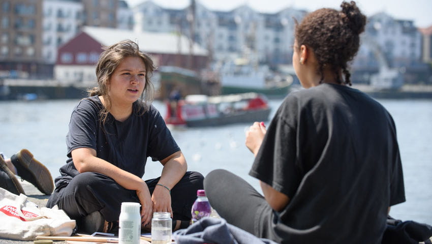 Students sitting by the harbourside