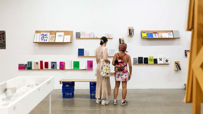 A couple of people looking at books on a shelf in the Arnolfini