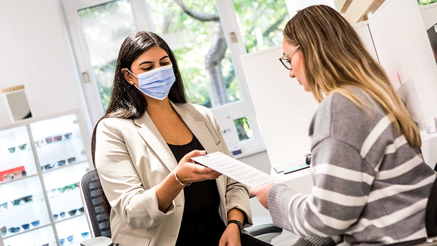 A student Optometrist discussing eye test results with a patient.