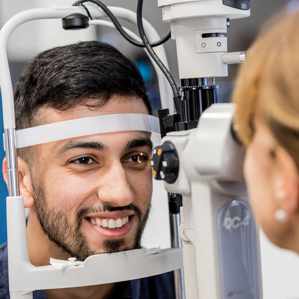 Optometry student using eye test equipment.