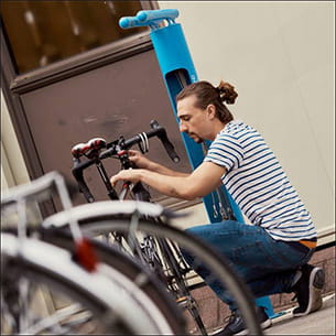 Man in a stripy t-shirt crouching down next to a bike.