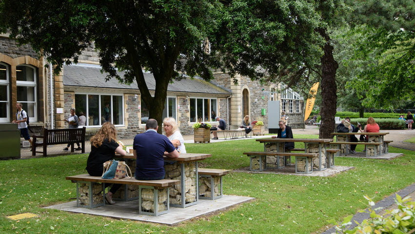 Students sitting outside on park benches in glenside grounds