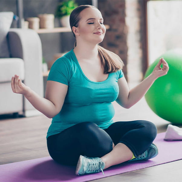 Girl sitting cross legged on a yoga mat meditating