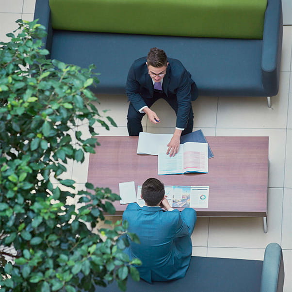 Aerial shot of two men dressed in suits sitting opposite each other going over business papers