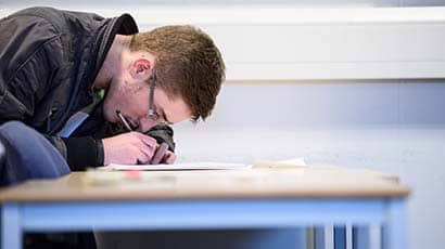 Student sat at a desk writing notes