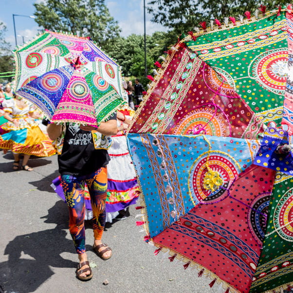 People holding colourful parasols at a street festival.