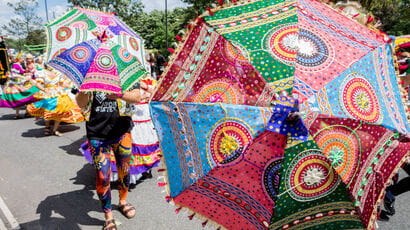 People holding colourful parasols at a street festival.