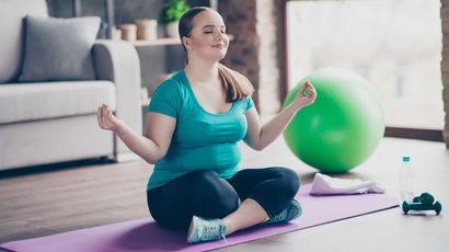 Person meditating on a mat on the floor.