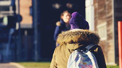 Student walking outside in the winter sun