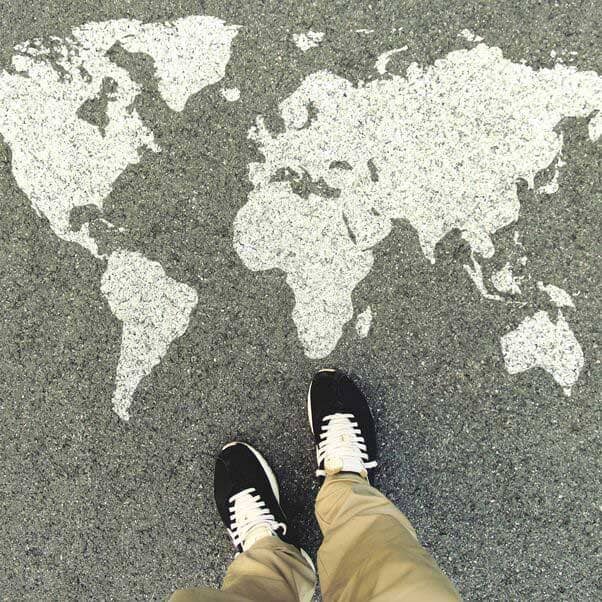 View looking down at person's feet next to an atlas design on the pavement.