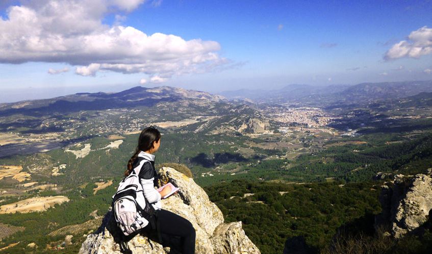 Female student sat on mountain top looking at the views of Alicante.