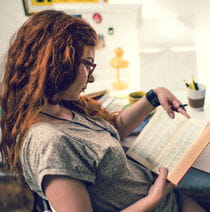 Female student studying at their desk reading a book.