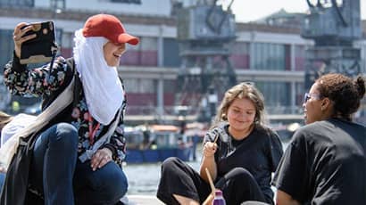 Three students hanging out and chatting by Bristol Harbourside.