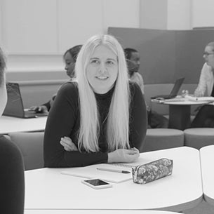 Student smiling while sat at a study space.