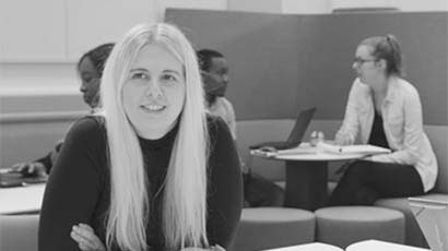 Black and white picture of a student sat behind a desk.