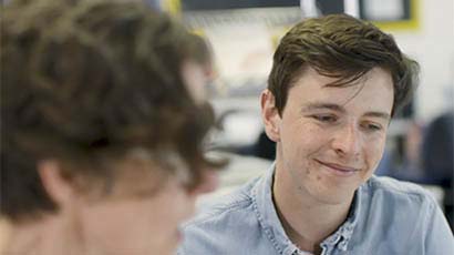Man smiling whilst sat with colleague