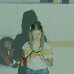 Persons studying their nails at an ice rink.